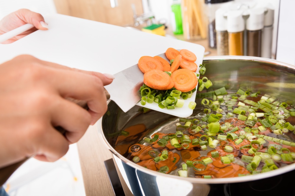 Putting Chopped Vegetables In a soup pot At Kitchen